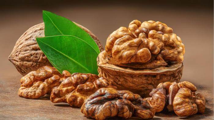 Des noix entières et décortiquées posées sur une table en bois