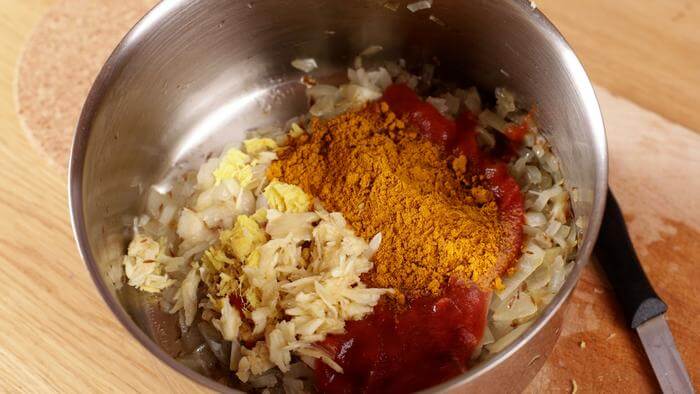preparation-de-base-aromatique-au-curry Mélange d'épices, oignons et choux dans une casserole pour une base de curry.